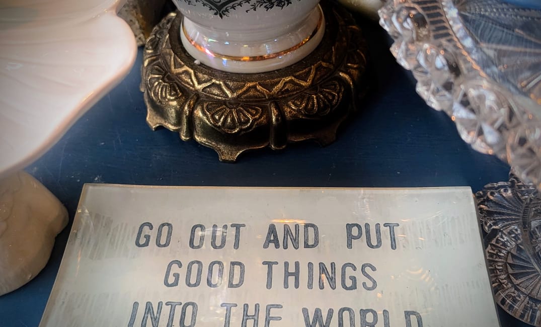 Glass plate on table that reads 'Go Out and Put Good Things Into The World'