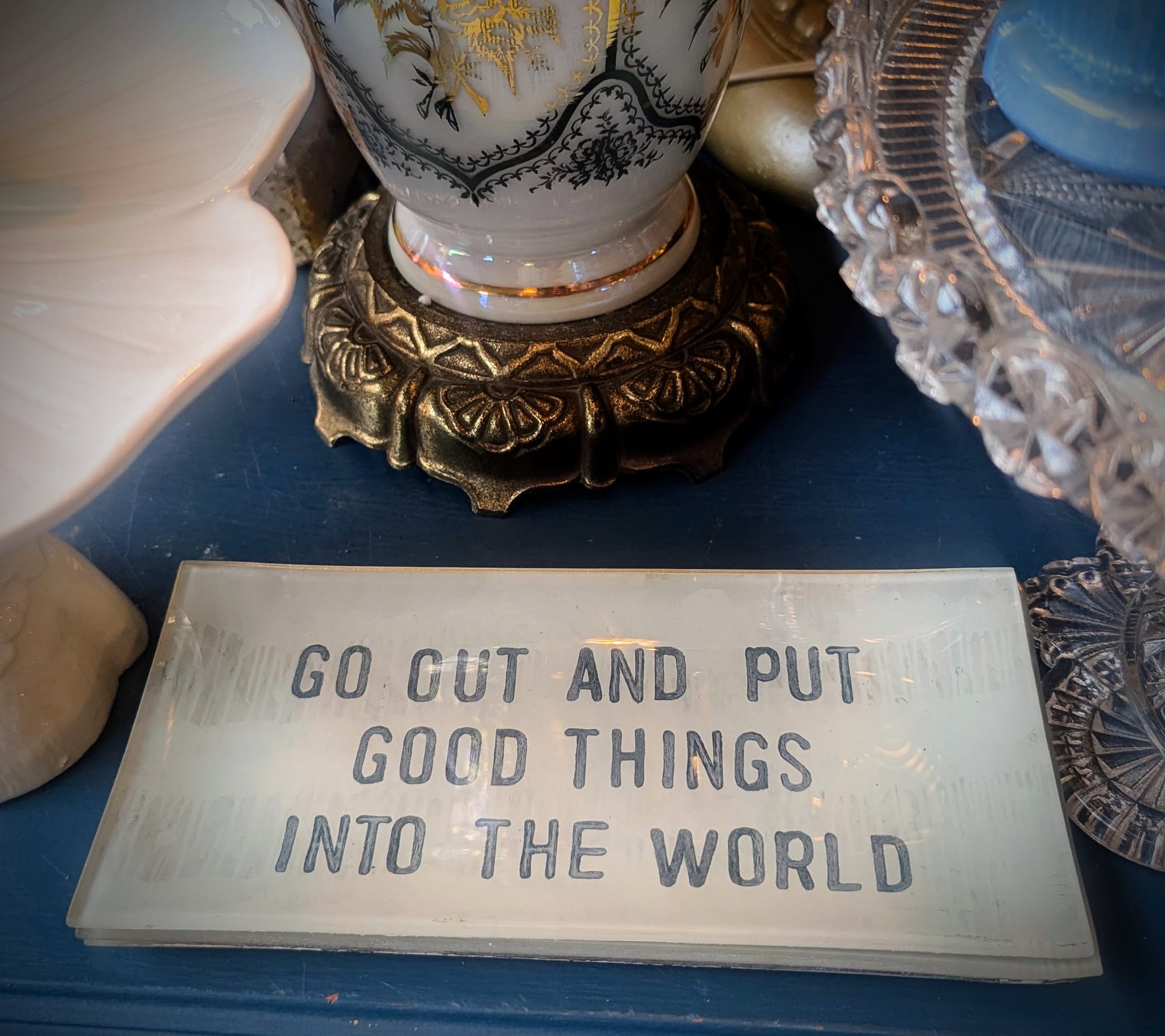 Glass plate on table that reads 'Go Out and Put Good Things Into The World'